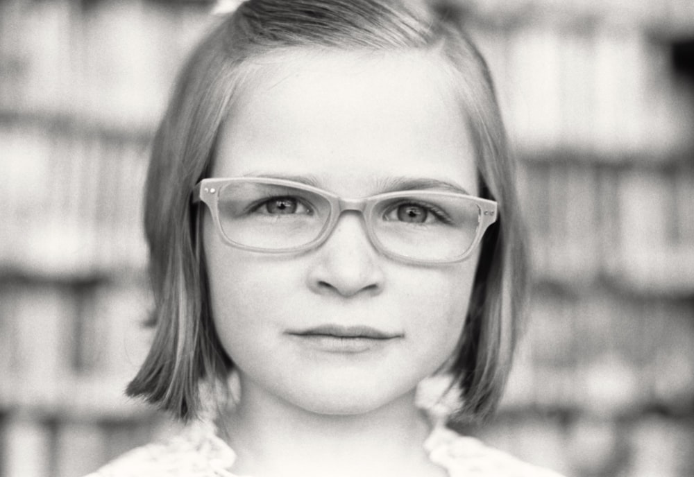 안경을 쓴 소녀의 그레이스케일 사진
