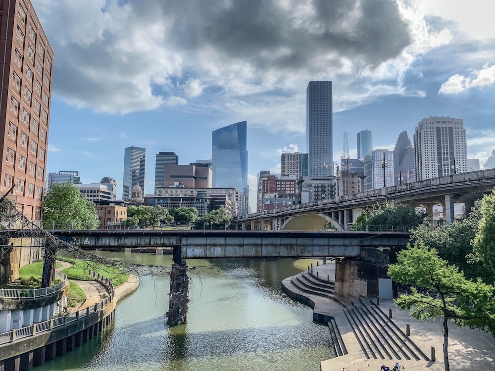 bridge over river near city buildings during daytime