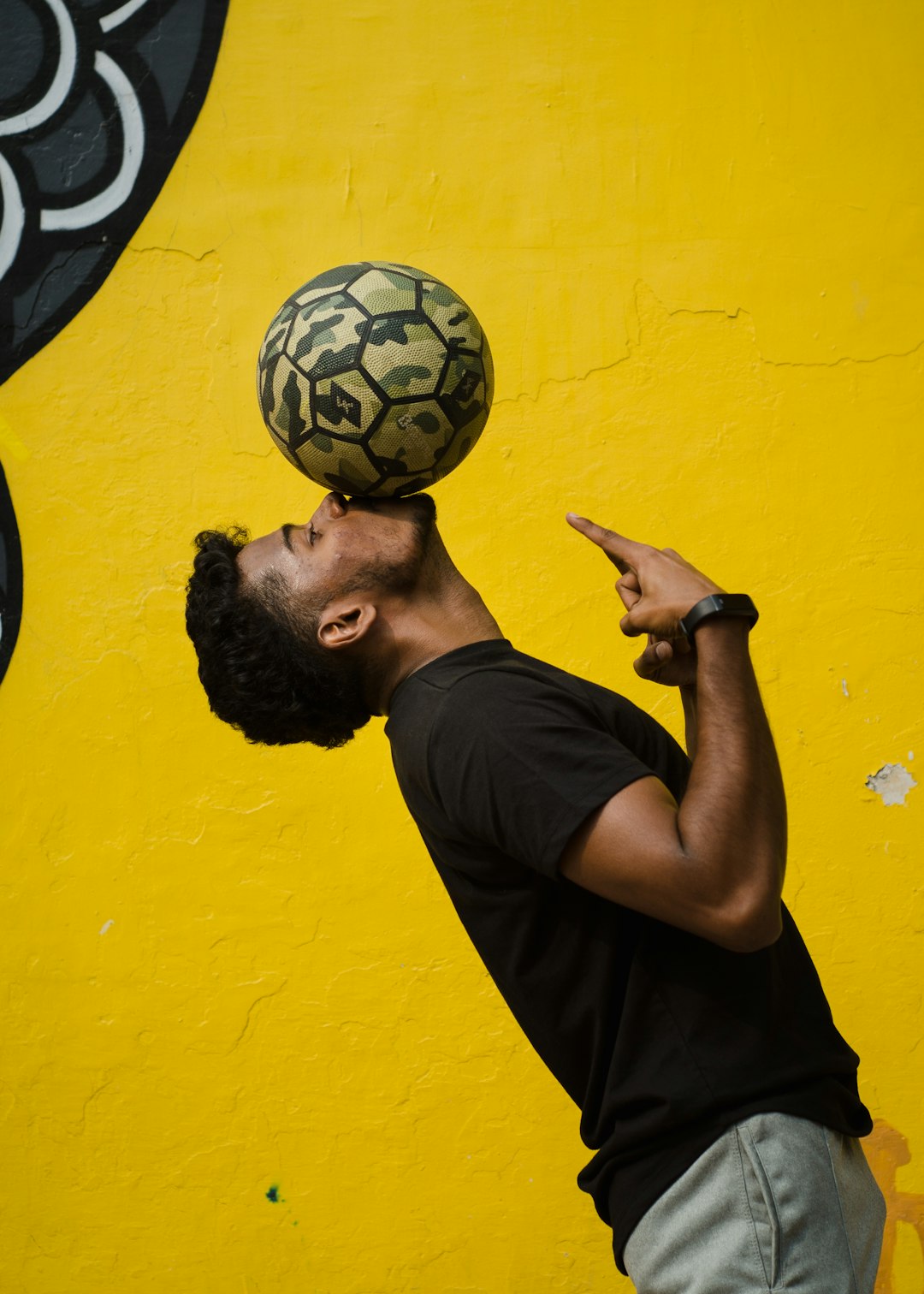 man in black crew neck t-shirt holding black and white soccer ball