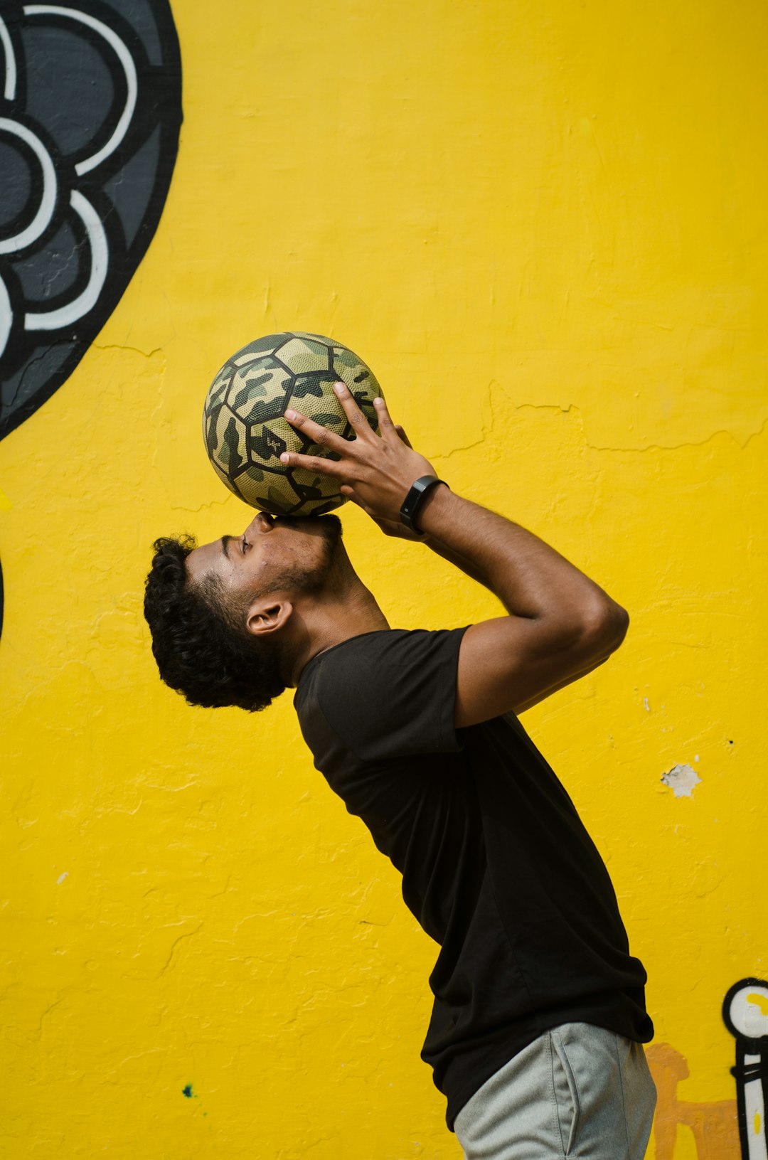 man in black t-shirt holding soccer ball