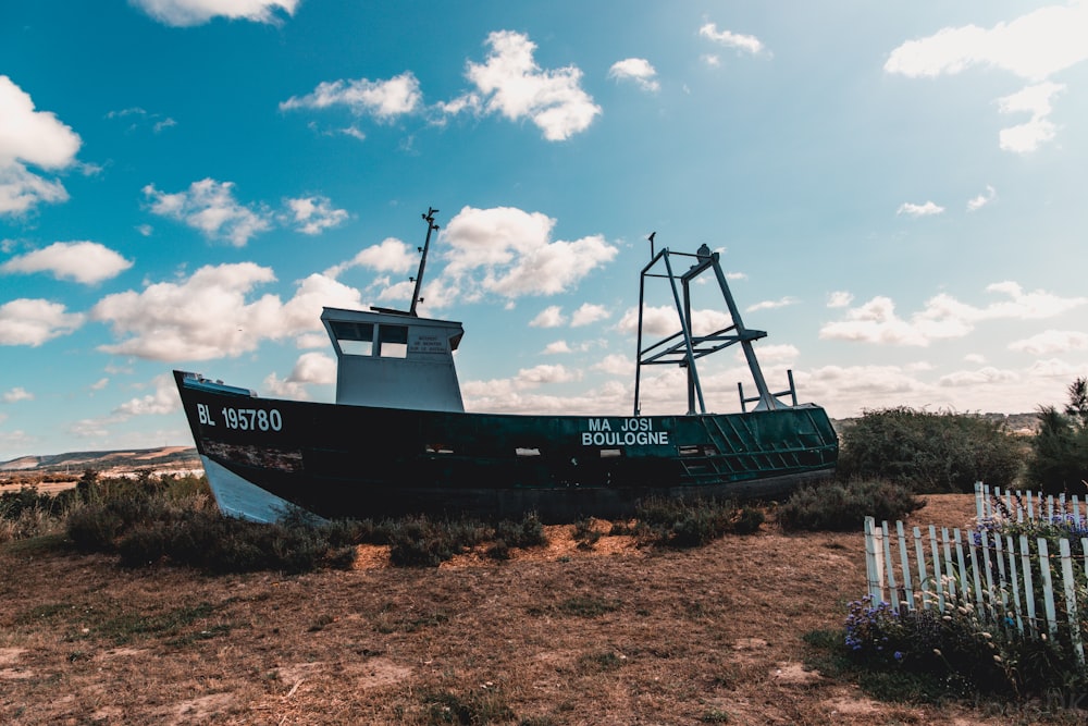 blue and white ship on brown field under blue and white cloudy sky during daytime