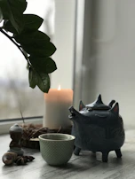 A cozy scene with a hand-thrown ceramic teapot surrounded by soft cushions and warm light.