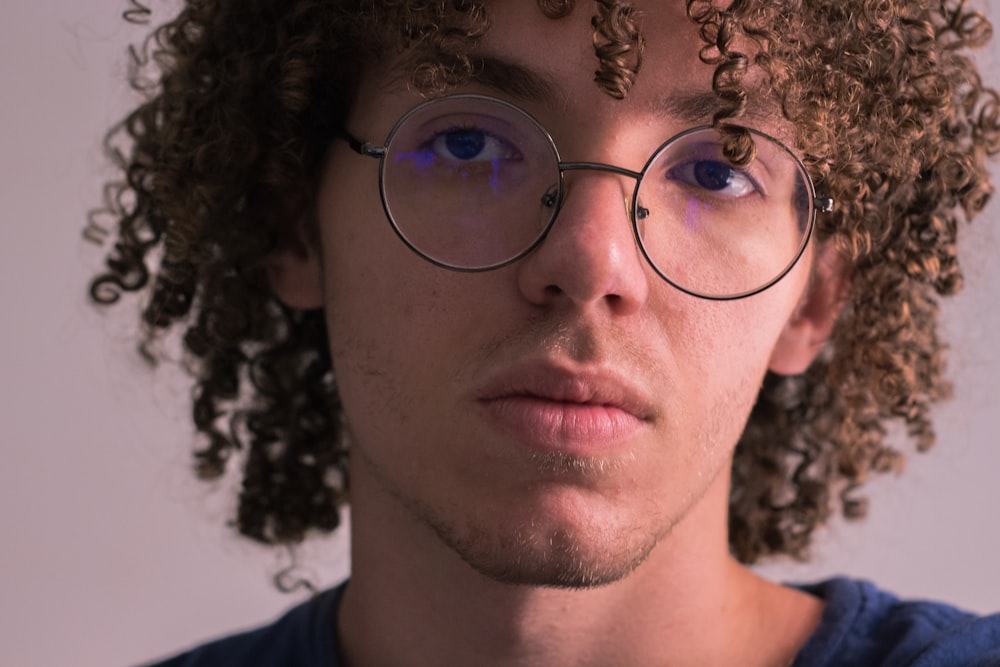 man in blue crew neck shirt wearing silver framed eyeglasses