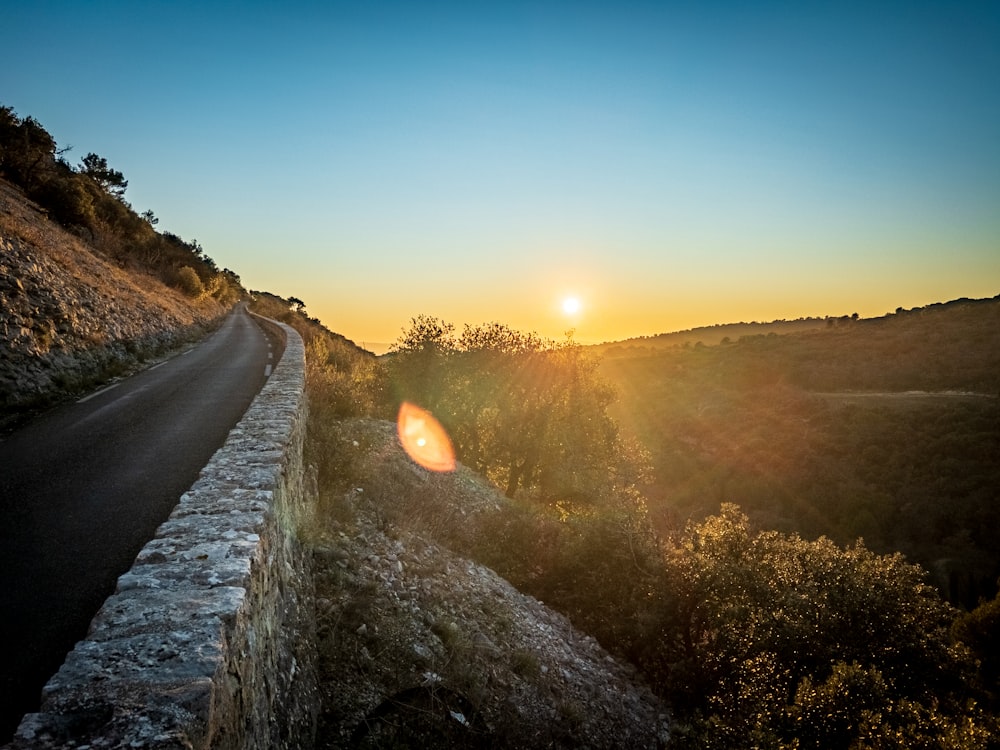 Graue Betonstraße zwischen grünem Grasfeld bei Sonnenaufgang