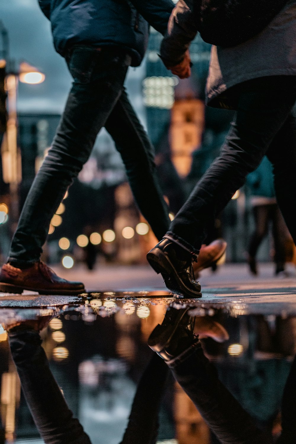 person in black pants and brown leather boots standing on brown wooden plank during night time