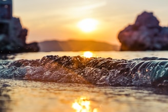 Children praying together with gentle ocean waves and sunset in the background.