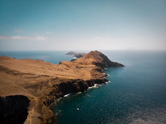 brown mountain beside blue sea under blue sky during daytime in Madeira Portugal