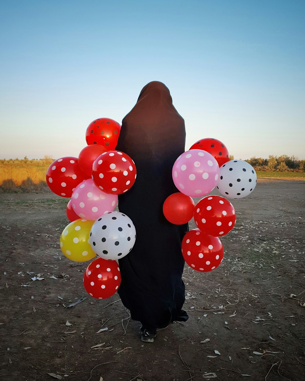 person holding red and white polka dot balloons