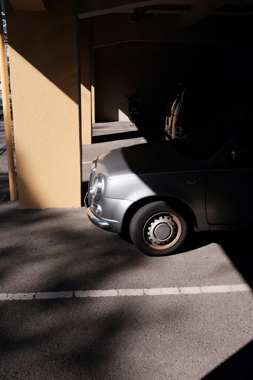 silver car parked beside yellow concrete building