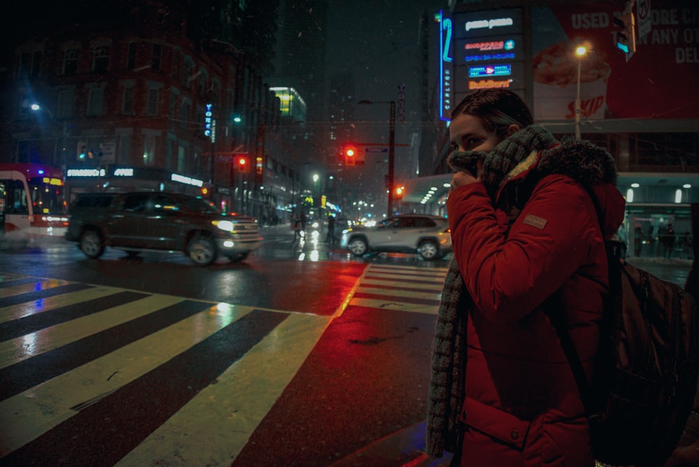 man in brown coat standing on pedestrian lane during night time