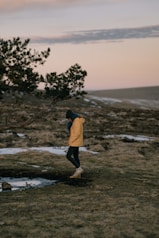 person in yellow hoodie standing on seashore during daytime