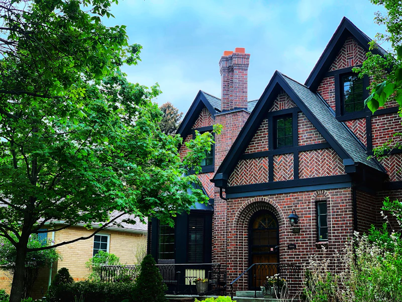 Brick home framed by leafy green trees