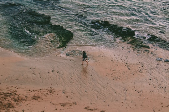 2 people walking on beach shore during daytime in Estoril Portugal