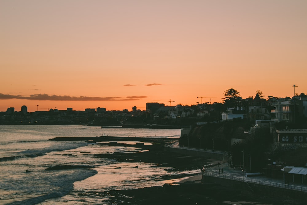 silhouette of buildings near body of water during sunset