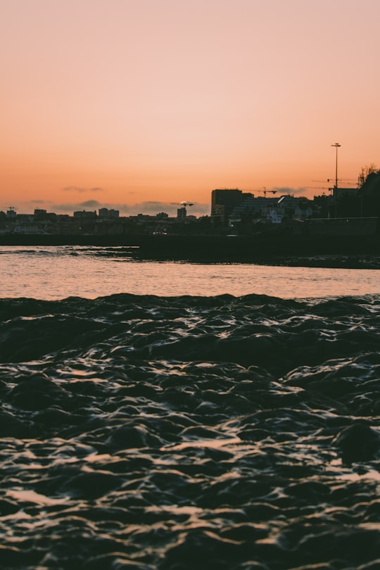 silhouette of city buildings near body of water during sunset in Estoril Portugal