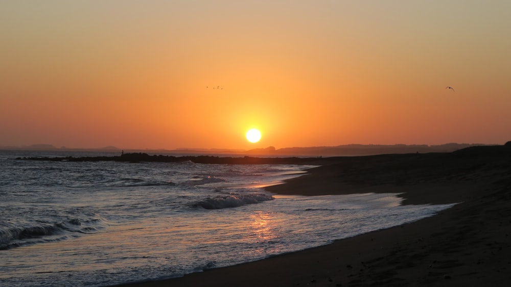 sea waves crashing on shore during sunset