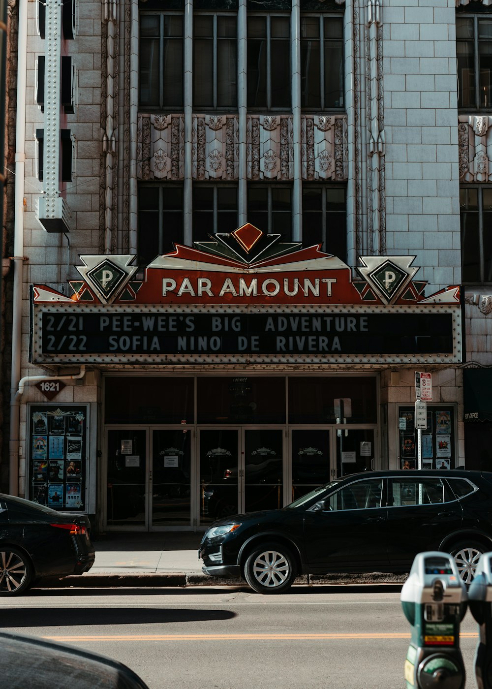 a movie theater with cars parked in front of it