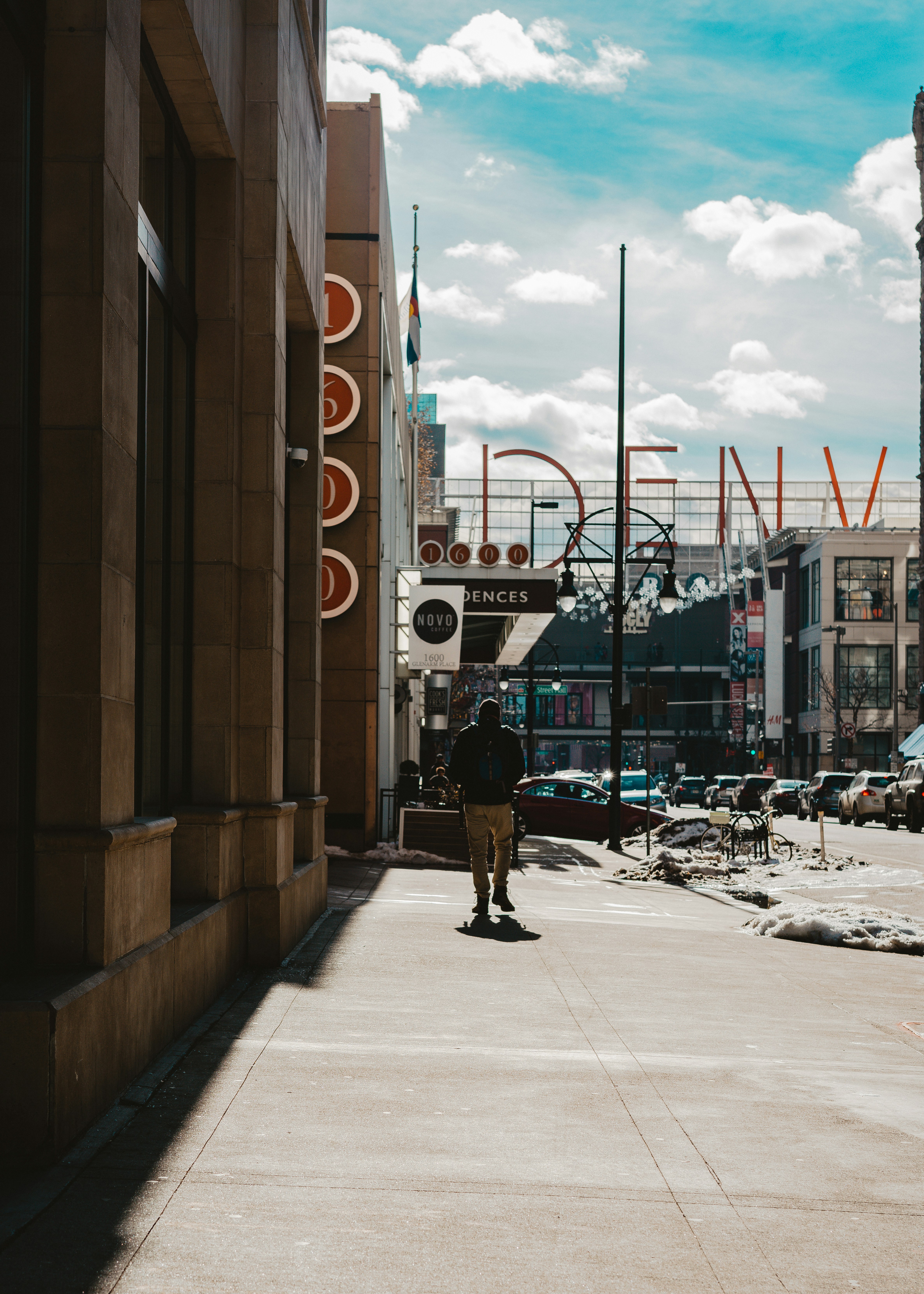man in black jacket and black pants walking on sidewalk during daytime
