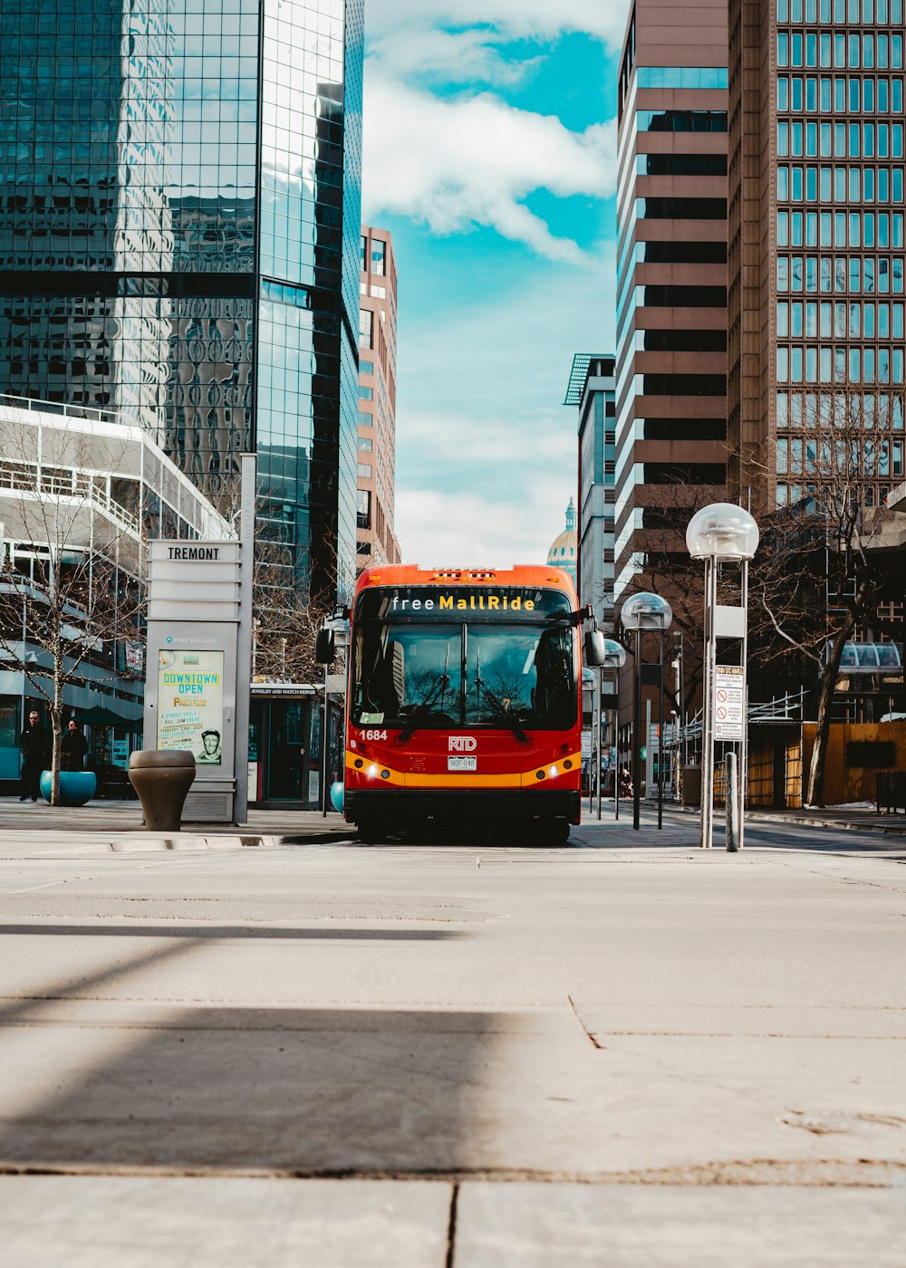 red and black bus on road near high rise buildings during daytime