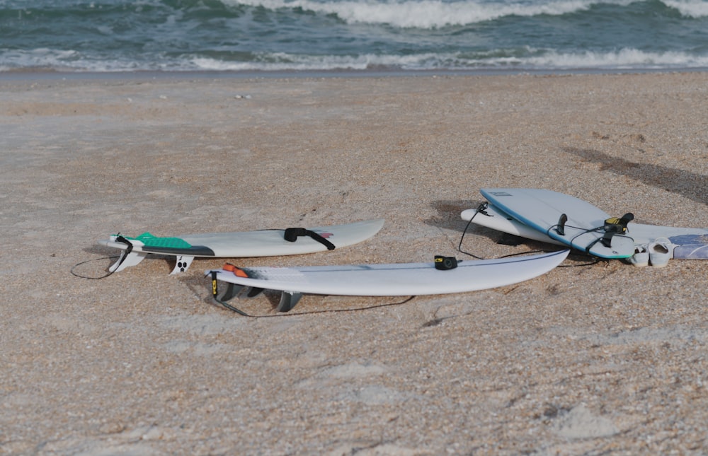 weißes und blaues Surfbrett tagsüber am braunen Sandstrand