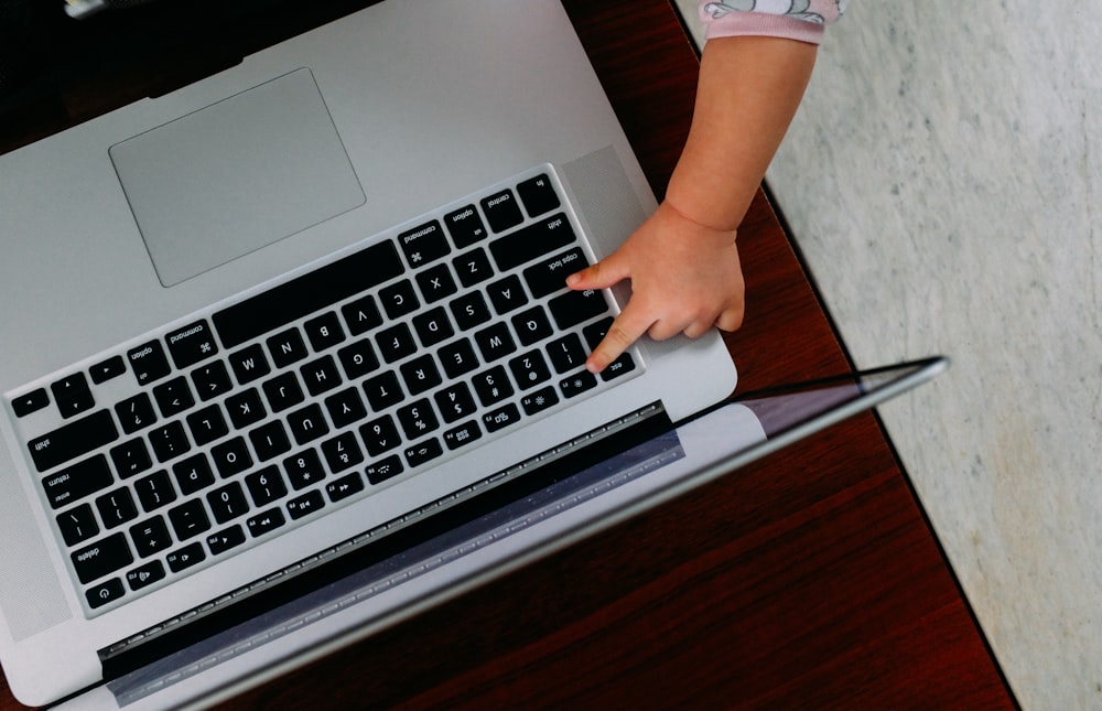 Person, die das MacBook Pro auf einem braunen Holztisch benutzt