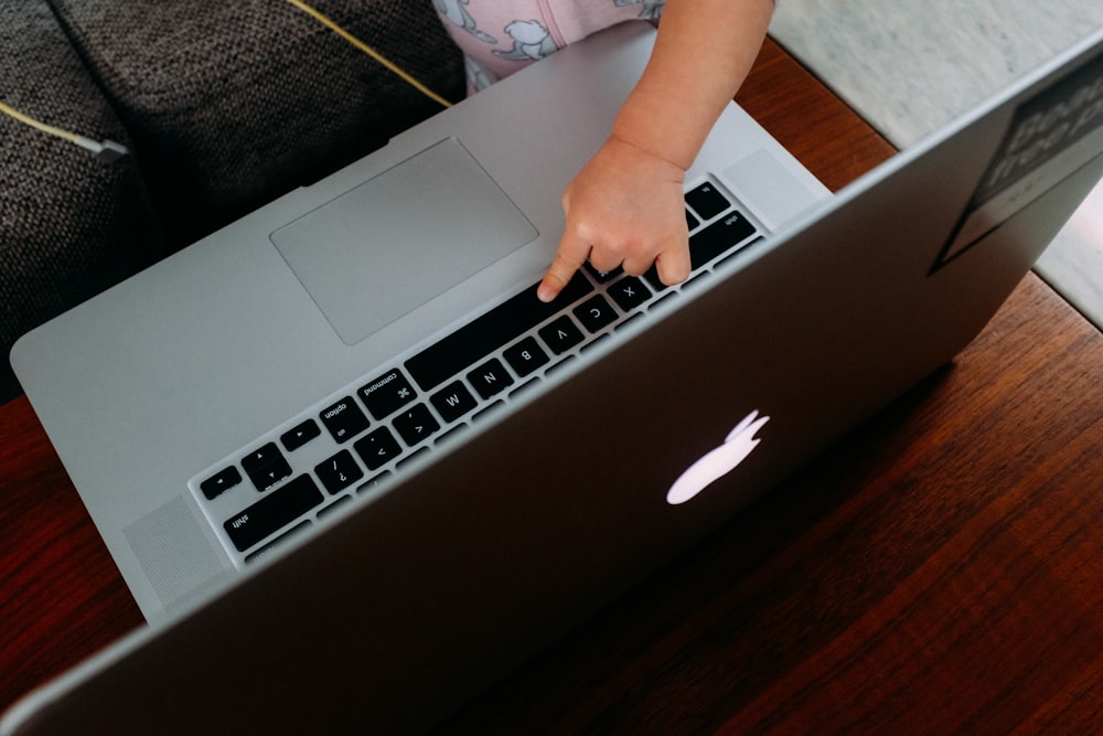 茶色の木製のテーブルでMacBookを使用している人