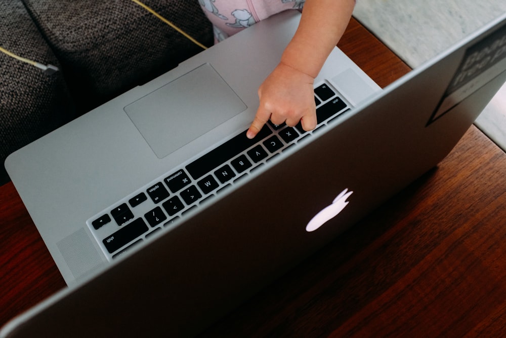 Personne utilisant un MacBook sur une table en bois marron
