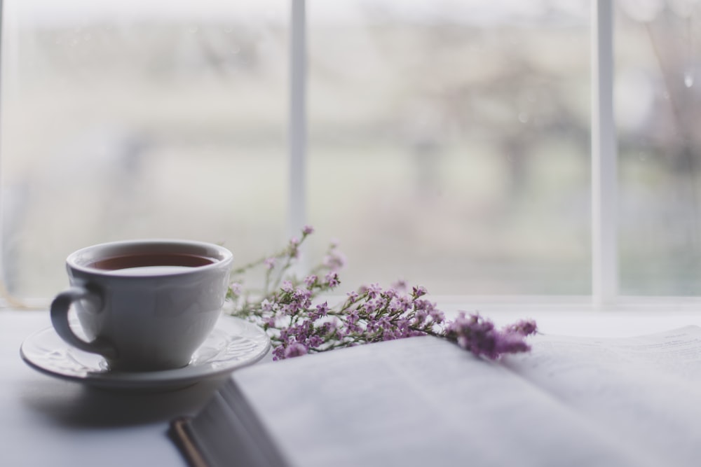 taza de té de cerámica blanca sobre platillo de cerámica blanca sobre mesa