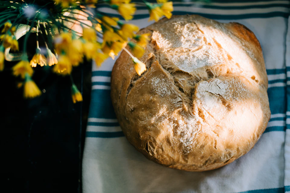 Freshly baked bread rests on a blue and white striped towel on a black surface