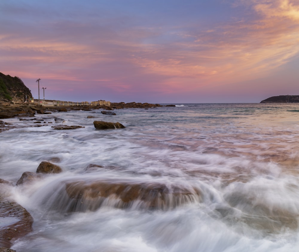 Olas del océano rompiendo contra las rocas durante la puesta de sol