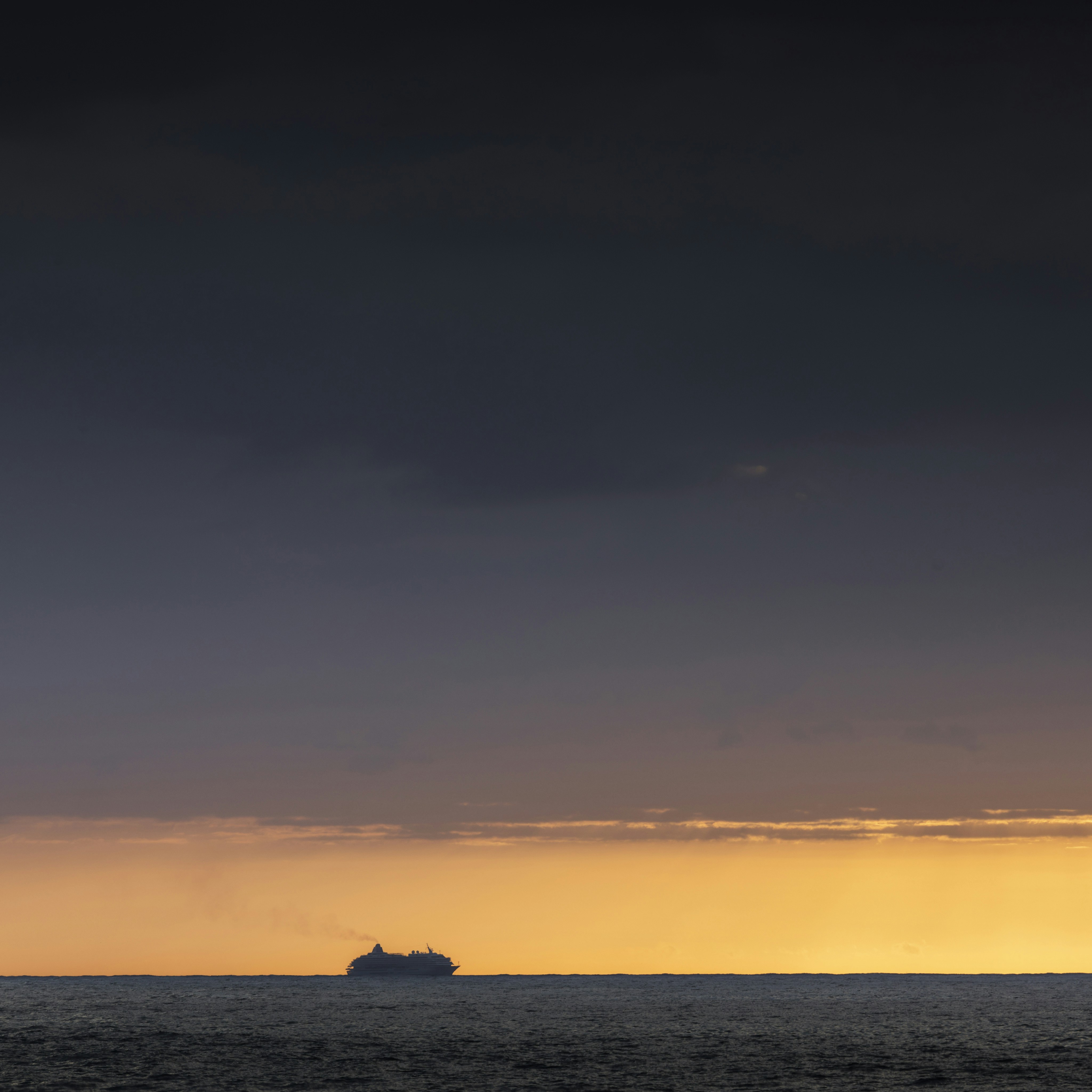 silhouette of a person on a rock in the middle of the sea during sunset