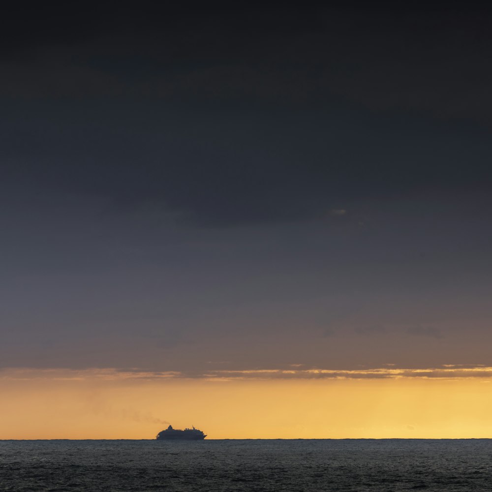 Silhouette einer Person auf einem Felsen mitten im Meer während des Sonnenuntergangs