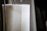 A close-up of a vertically oriented white paper towel roll, resting on a metal holder with a focus on the texture and material of the towel.