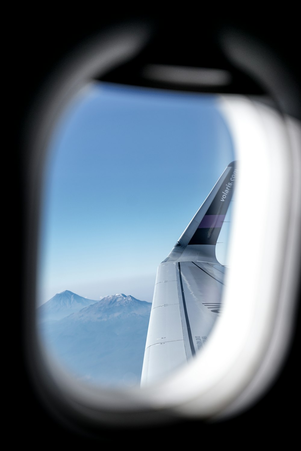 日中の雪に覆われた山々の飛行機の窓からの眺め