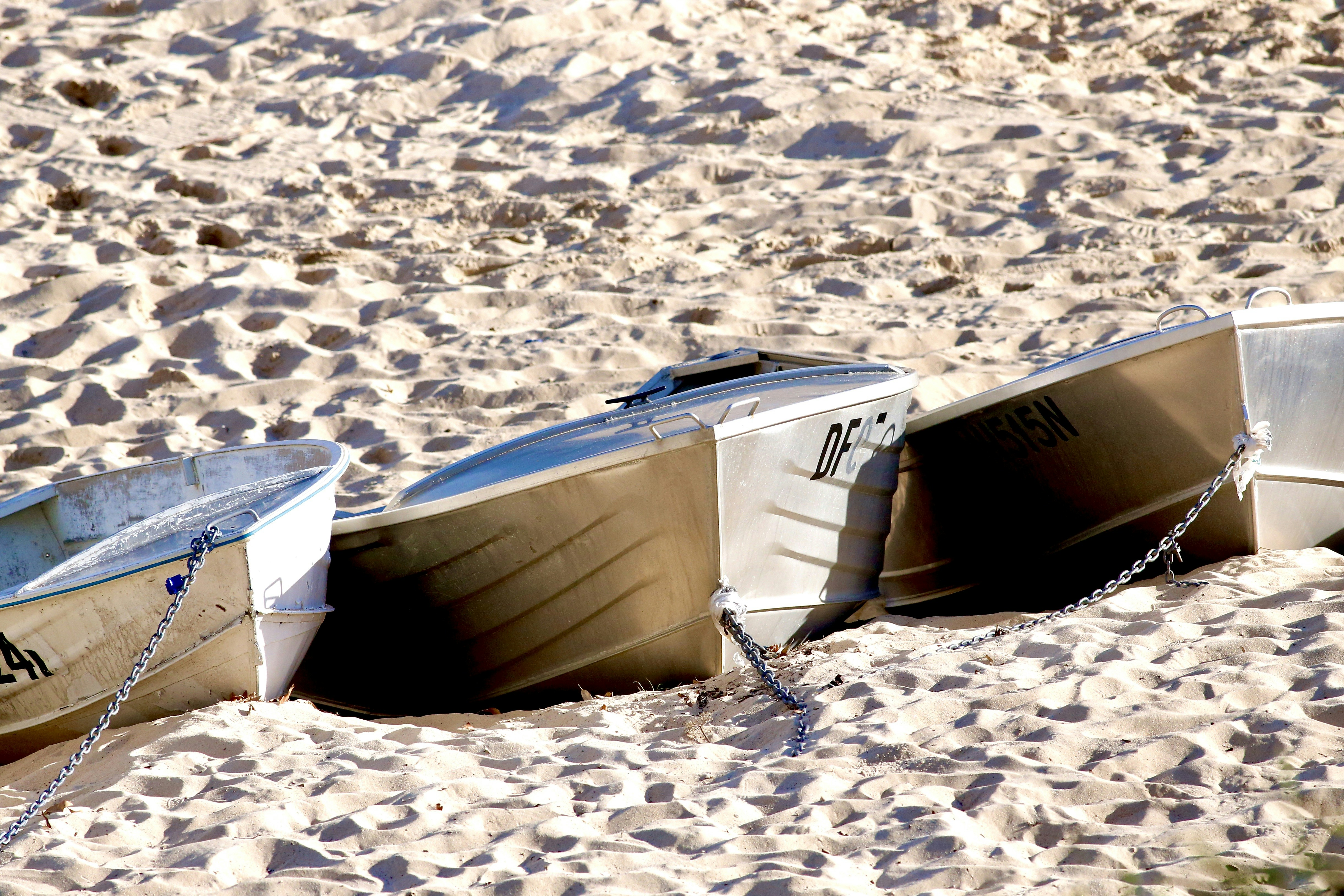 white and blue boat on white sand during daytime