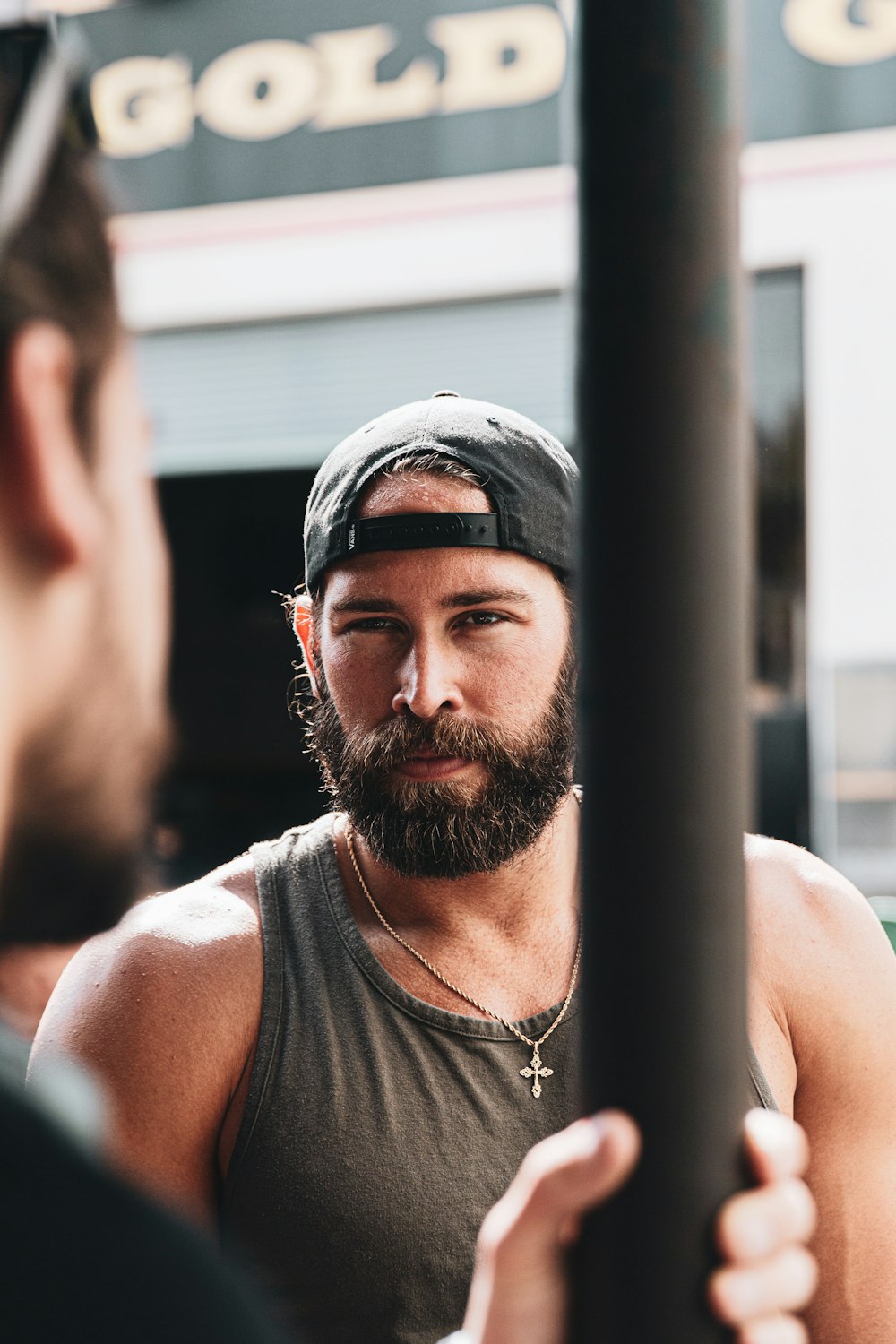 man in grey tank top wearing black fitted cap