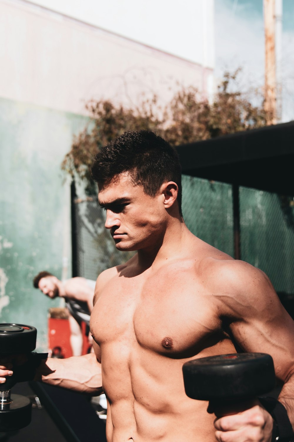 topless man standing near black and red drum set