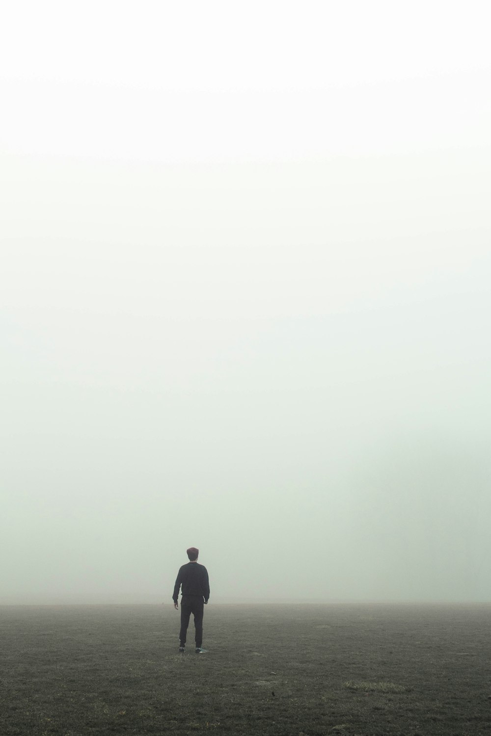 man in black jacket standing on foggy weather