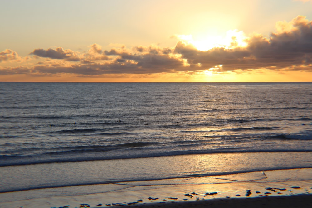 body of water under cloudy sky during sunset