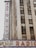 A tall building is partially visible, featuring a vertical neon sign with the words 'Radio City' prominently displayed. Below, another sign reads 'Music Hall' with the text 'Radio City' running horizontally across a marquee. The building exterior is composed of concrete and glass windows.