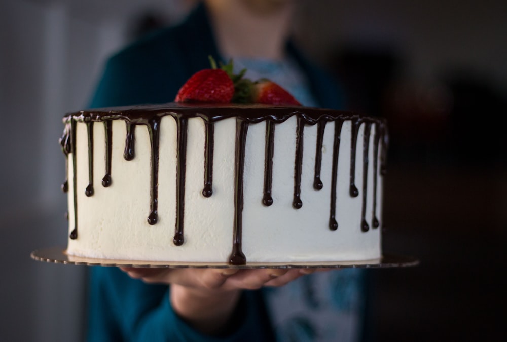 person holding brown wooden tray with strawberries