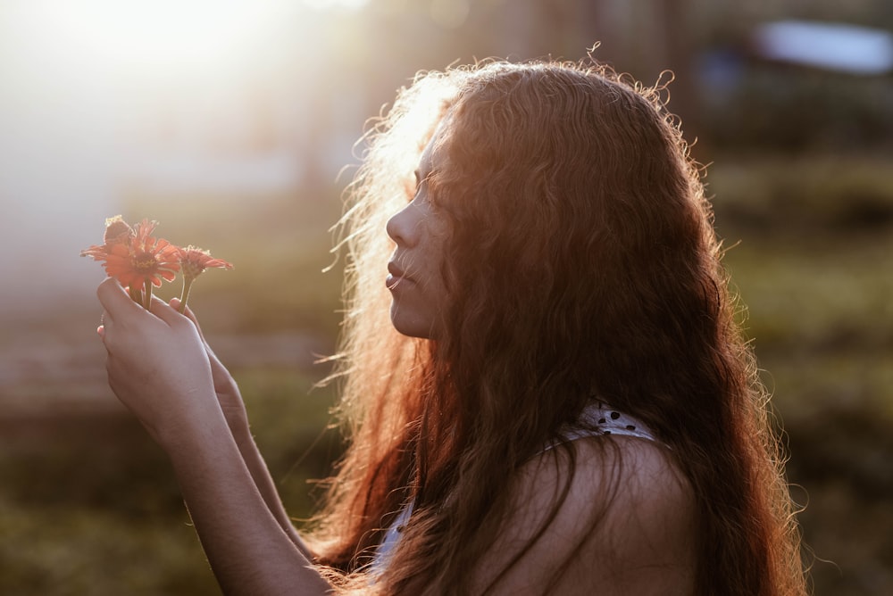 woman in white tank top holding brown leaf during daytime