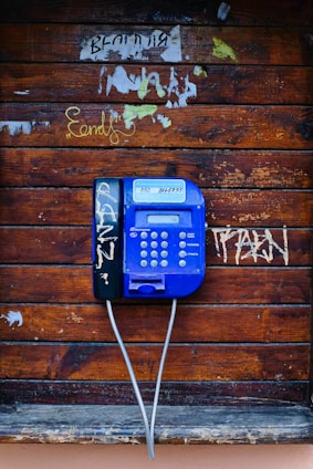 blue telephone on brown wooden wall