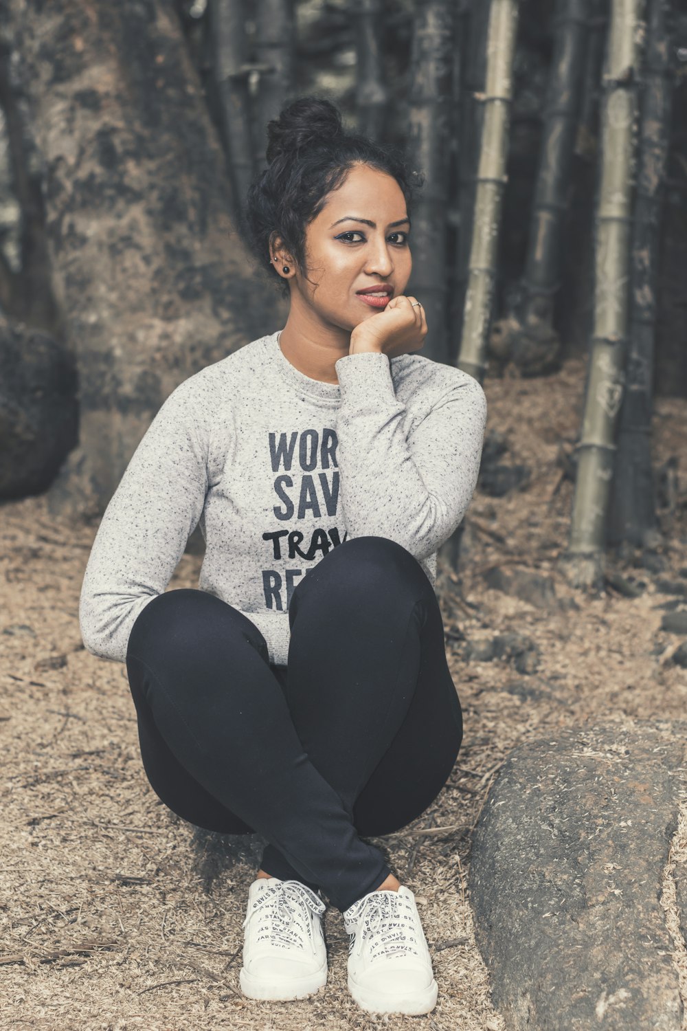 woman in gray and black long sleeve shirt and black pants sitting on brown rock during