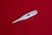 A digital thermometer with a white body and a small display screen is placed on a smooth red background. The thermometer has a sleek, elongated design with a metallic tip.