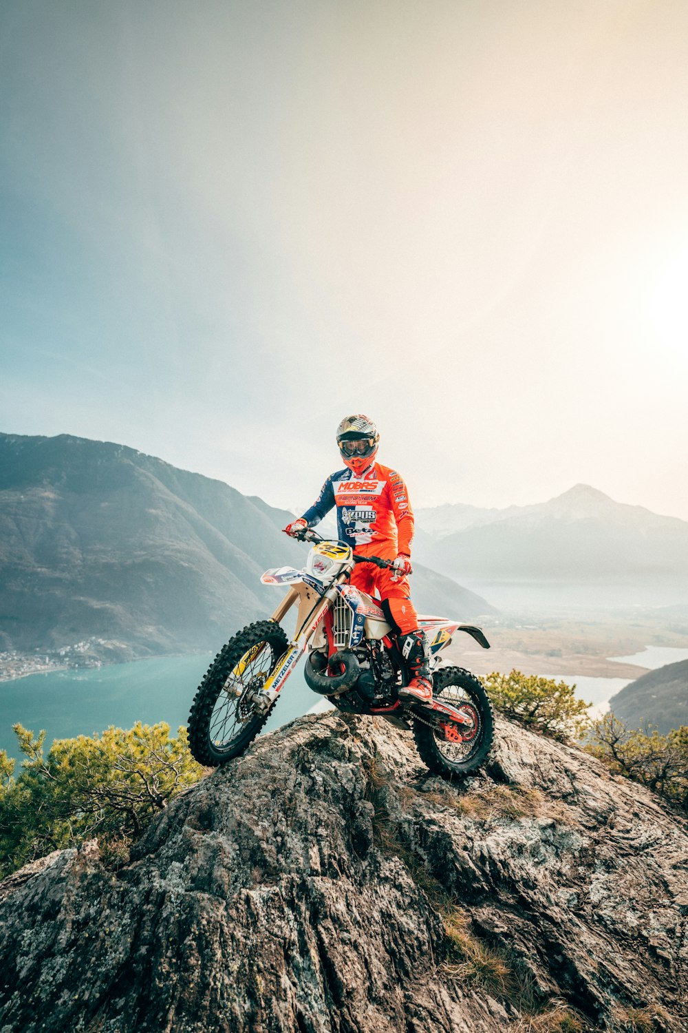 Mann im rot-weißen Motocross-Anzug fährt tagsüber Motocross-Dirtbike am Berg