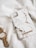 A stylish phone case with a marble pattern lies on a soft, white fabric. Next to it, there is a sophisticated gold wristwatch with a white clock face.