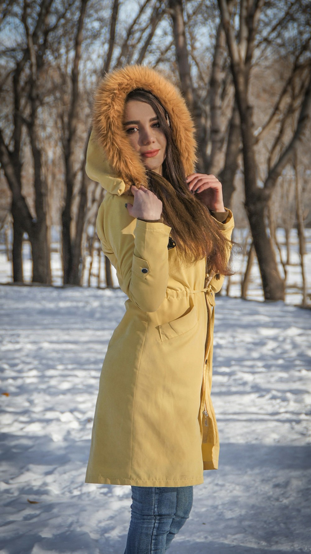 woman in yellow coat standing on snow covered ground during daytime