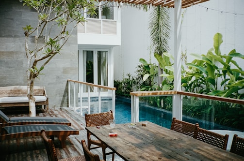 brown wooden table with chairs near swimming pool