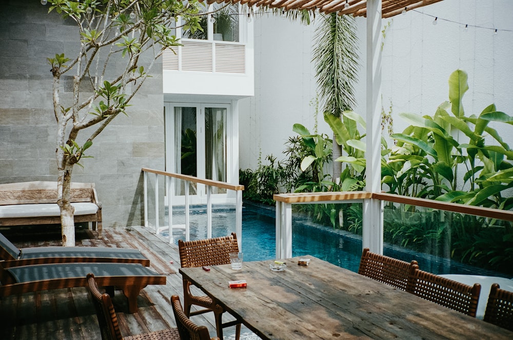 brown wooden table with chairs near swimming pool